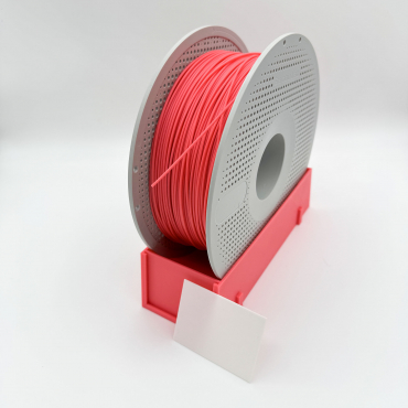 Pink 3D printing filament spool stand holding a grey Bambu Lab reusable spool, featuring a blank white label card in the foreground for filament identification printing settings.