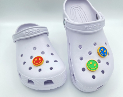 Red, green, and blue smiley face charms on white clogs.