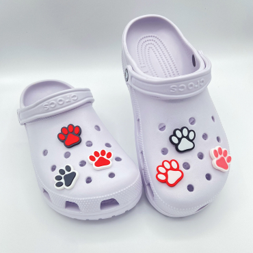 Collection of colorful 3D printed paw print charms on purple shoes.