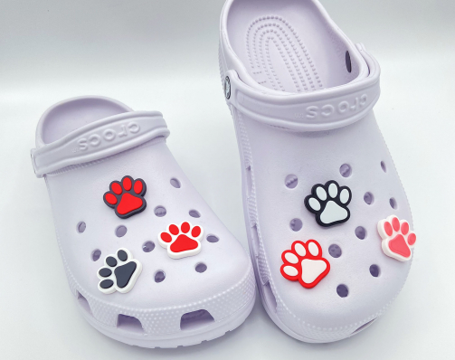 Collection of colorful 3D printed paw print charms on purple shoes.