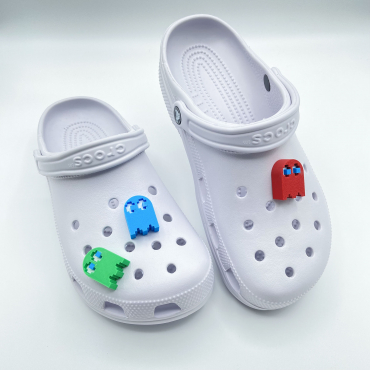 Red, blue, and green 3D printed ghost charms on a pair of white shoes.