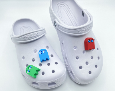 Red, blue, and green 3D printed ghost charms on a pair of white shoes.